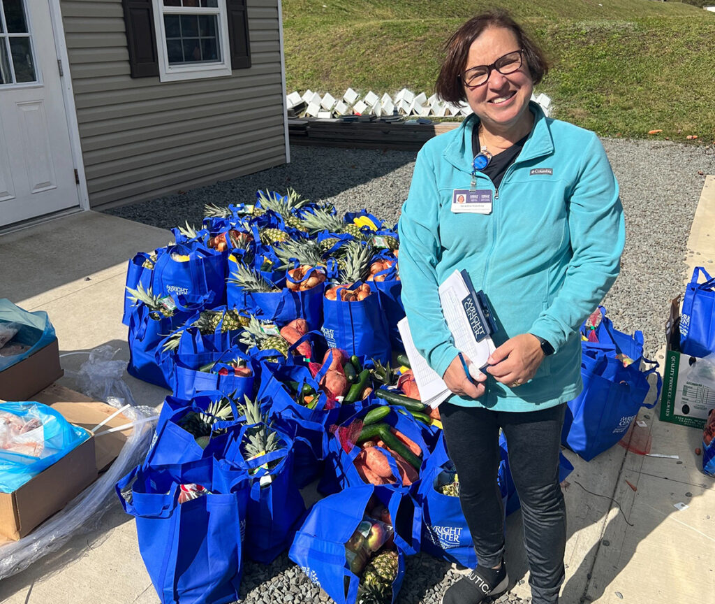 Gerri McAndrew from PCE standing in front of donated food bags 