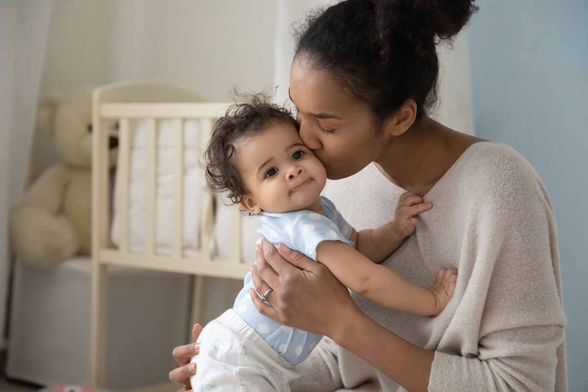 Loving biracial mom hug and kiss little baby