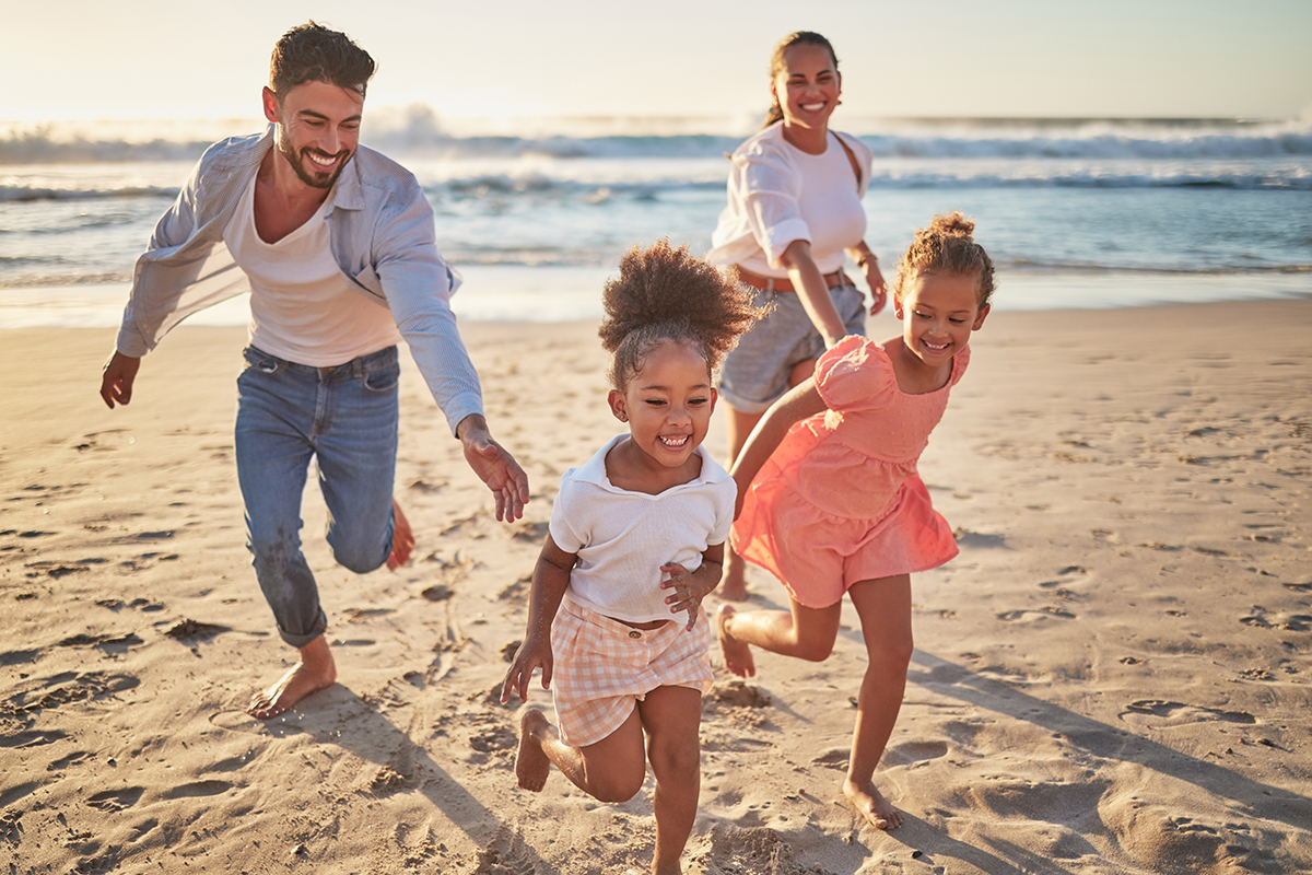 Family, beach and kids with parents running on sand on summer holiday. Mom, dad and children at ocean at sunset in Mexico. Freedom, fun and vacation, happy man and woman playing with girls at the sea