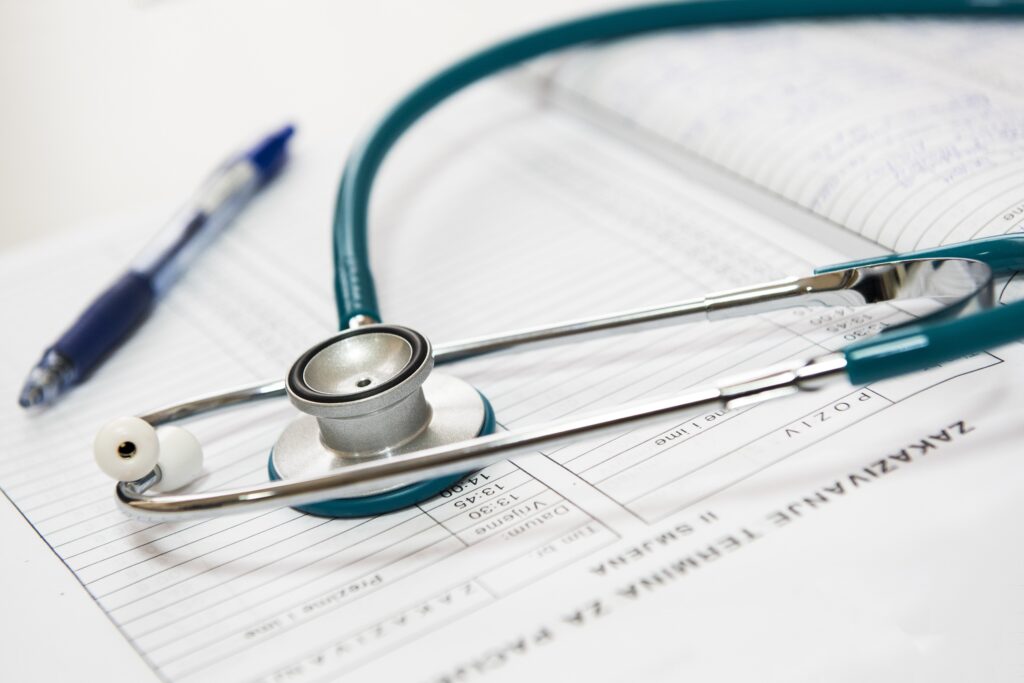 stethoscope and pen on a pile of medical forms